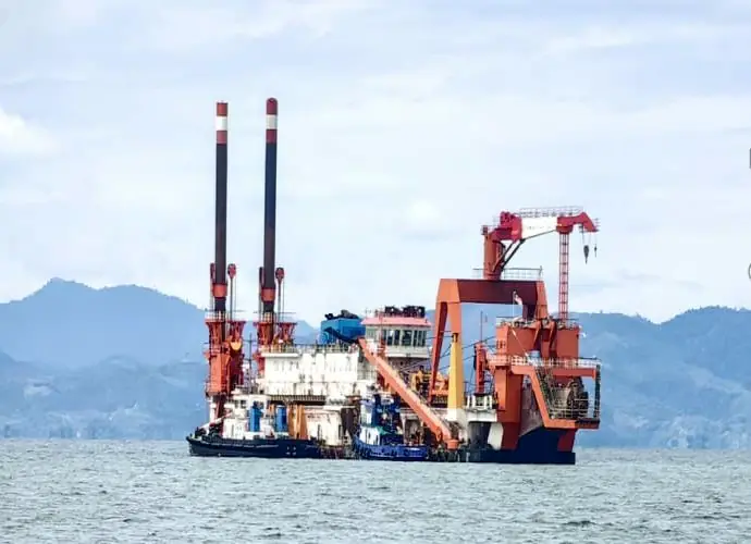 Dredger and tug working with cranes at sea